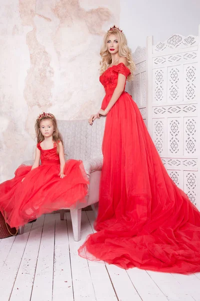 妈妈和女儿穿着红色的节日礼服在白色的家庭内部 — 图库照片