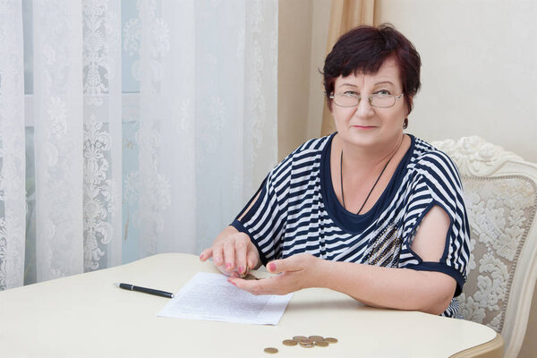 Old woman sitting at table and counting coins. Pleasing appearance older woman