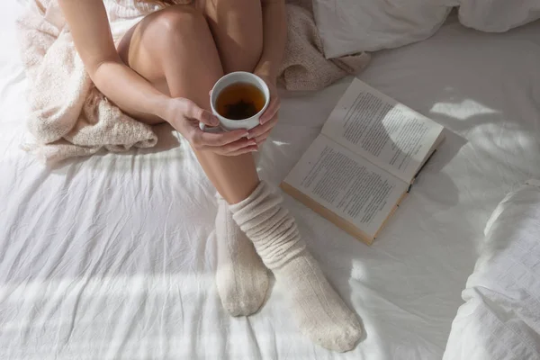 Zbliżenie Piękne Kobiece Nogi Łóżku Kobieta Picie Herbaty Czytanie Książki — Zdjęcie stockowe