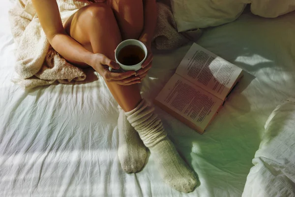 Zbliżenie Piękne Kobiece Nogi Łóżku Kobieta Picie Herbaty Czytanie Książki — Zdjęcie stockowe