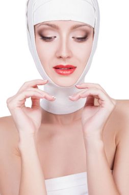 Başında, güzel yüz makyaj ile bandaj ile güzel genç kadın. Güzel kadın yüzüne kırmızı ruj beyaz arka plan üzerinde izole dudaklarında bandaj portresi