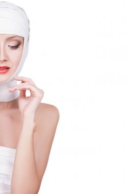 Başında, güzel yüz makyaj ile bandaj ile güzel genç kadın. Güzel kadın yüzüne kırmızı ruj beyaz arka plan üzerinde izole dudaklarında bandaj portresi