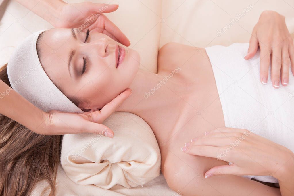 Portrait of young woman in spa environment, girl receiving face massage, relaxation and facial treatment