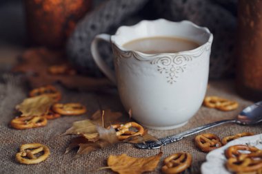 Sonbahar yaprakları, dumanı tüten fincan sıcak kahve ve sıcak bir eşarp