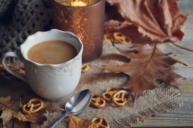 Sonbahar yaprakları, dumanı tüten fincan sıcak kahve ve sıcak bir eşarp