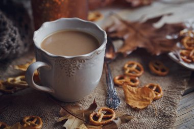 Sonbahar yaprakları, dumanı tüten fincan sıcak kahve ve sıcak bir eşarp