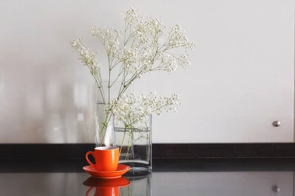 Flores blancas en una mesa en jarrones transparentes de vidrio con taza de — Foto de Stock
