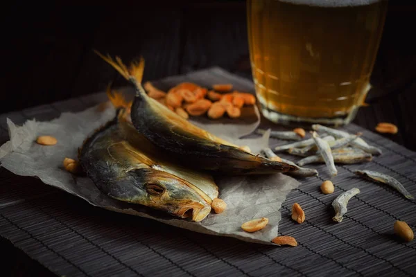 Beer and dried fish on dark wooden table. — Stock Photo, Image