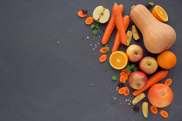 Fresh carrot, apple, pumpkin, orange, grapefruit on dark table. 