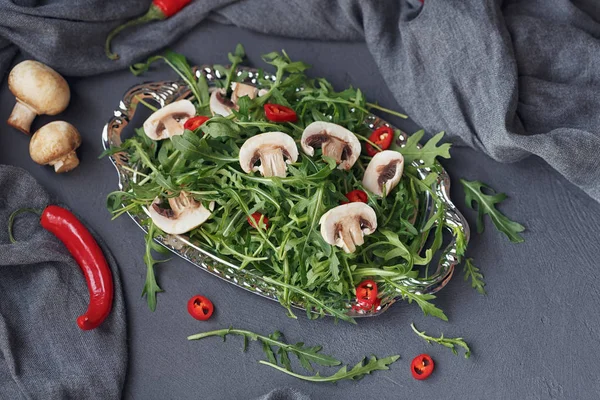 Свежая зеленая руккола с грибами и перцем чили на серебре — стоковое фото
