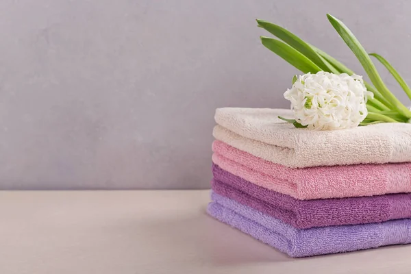 Montón de toallas de baño de colores con flor de jacinto en la espalda de luz — Foto de Stock