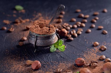 Fındık, kahve çekirdekleri ve koyu arka planda kakao tozu.