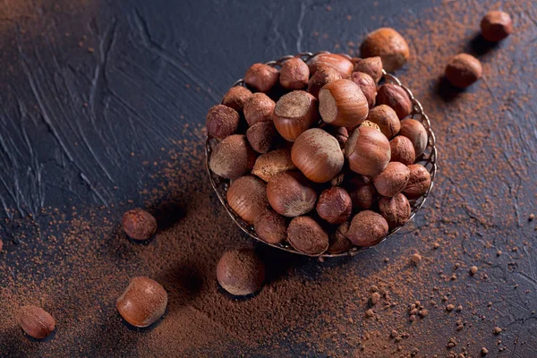 Haselnuss- und Kakaopulver vor dunklem Hintergrund. — Stockfoto