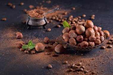 Fındık, kahve çekirdekleri ve koyu arka planda kakao tozu.