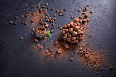 Fındık, kahve çekirdekleri ve koyu arka planda kakao tozu.