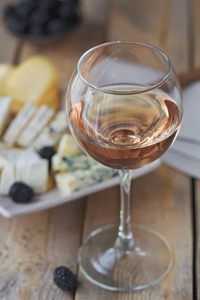 Ett glas rosévin serveras med ostbricka, björnbär och — Stockfoto