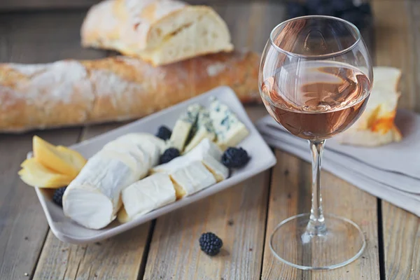 Um copo de vinho rosa servido com prato de queijo, amoras e — Fotografia de Stock