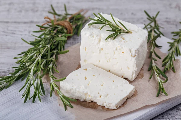 Čerstvý sýr feta sýr s rozmarýnem na bílé Dřevěné Servírovací deska — Stock fotografie