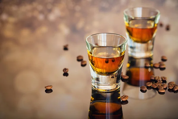 Cognac of likeur, koffiebonen en kruiden op een glazen tafel. — Stockfoto