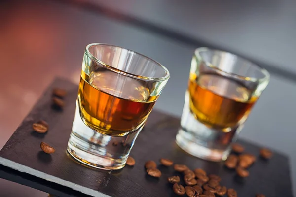 Cognac of likeur, koffiebonen en kruiden op een glazen tafel. — Stockfoto