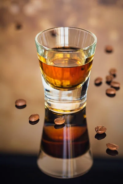 Cognac or liqueur, coffee beans and spices on a glass table. — Stock Photo, Image