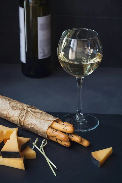 Käseteller serviert mit Crackern und einem Glas Weißwein auf Dar — Stockfoto