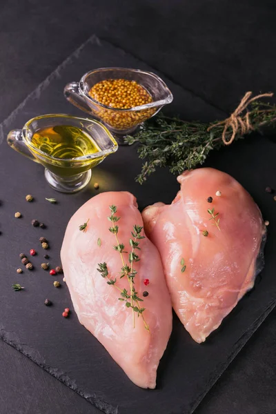 Raw chicken fillets with spices and herbs.