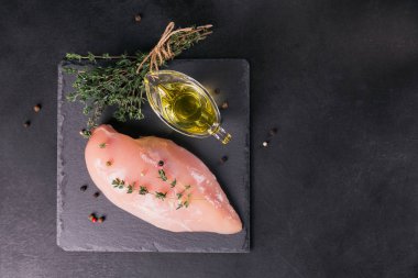 Baharat ve otlar ile siyah kesme tahtası üzerinde çiğ tavuk fileto. Pişirme malzemeleri. Doğal sağlıklı gıda kavramı. Metin için yer ile Üstten Görünüm