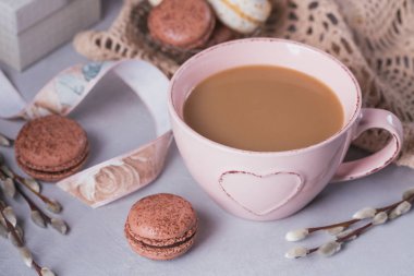 Pembe tatlı pastel Fransızca macaroons ile kupa kahve, hediye kutusu ve