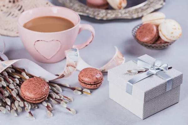 Pink coffee mug with sweet pastel french macaroons, gift box and