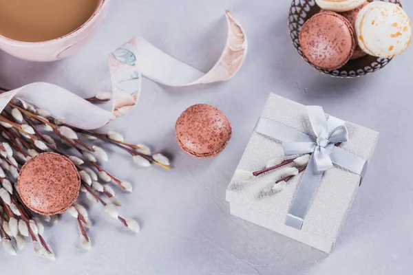 Pink coffee mug with sweet pastel french macaroons, gift box and pussy willow. Flat lay