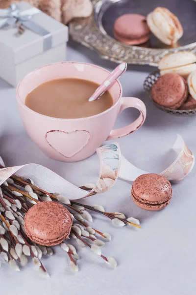 Pink coffee mug with sweet pastel french macaroons, gift box and