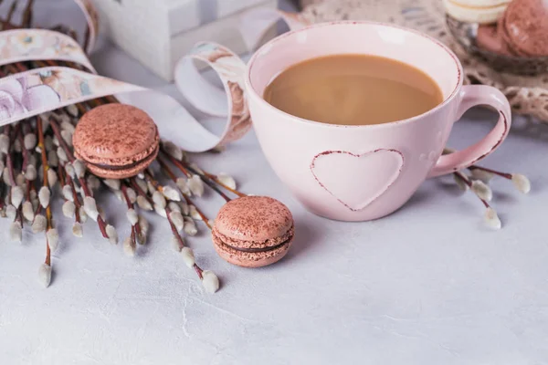 Pink coffee mug with sweet pastel french macaroons, gift box and