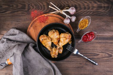 Soslar ahşap masa üzerinde tavada kızarmış tavuk budu. Üstten Görünüm