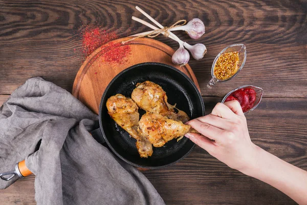 Gebratene Hühnerkeulen Mit Soßen Pfanne Auf Holztisch Frauenhand Hält Hühnerbein — Stockfoto