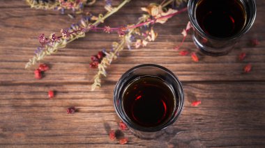 Koyu ahşap arka plan üzerinde alkollü içki iki kadeh. Farklı doğal maddeler ile bitkisel acı likörü. Üstten Görünüm