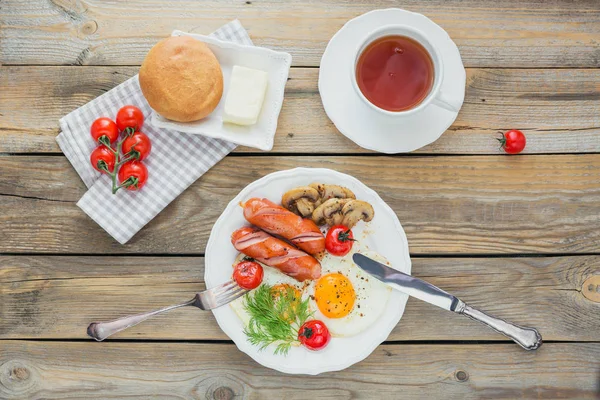 Pequeno-almoço inglês com ovos fritos, salsichas, cogumelos, tomates grelhados — Fotografia de Stock