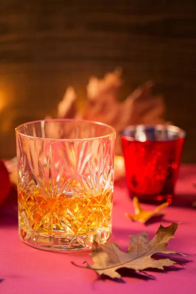 Whiskey, brandy or liquor, spices and autumn decorations on dark