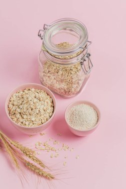 Bir kase kuru yulaf, yulaf ezmesi ve arka planda buğday. Sağlıklı yemek pişirmek. Genel giderler