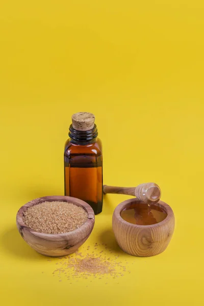 Ingredients for make homemade sugaring paste. Brown sugar, honey and oil on yellow background. Beauty concept