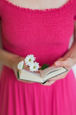 Elinde küçük bir kitap ve çiçek tutan bir kız. Boş zamanlarında okumak ve eğitim. 