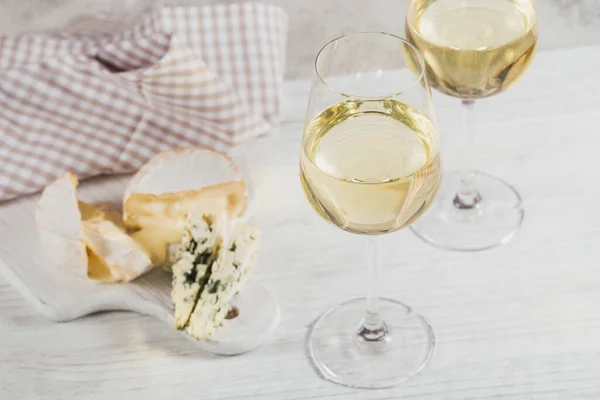 Bílé víno podávané se sýrovým talířem na světlém pozadí. Dvě sklenice vino verde. — Stock fotografie