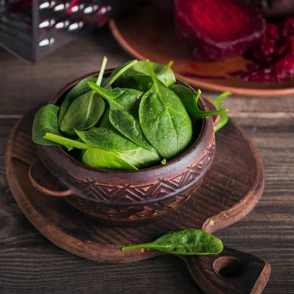 stock image Ingredients for making healthy vegan food with fresh green spinach and chopped beetroot in clay plates.