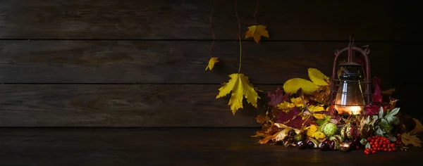 Humeur d'automne avec lampe antiquités au kérosène. Nature morte de feuilles d'automne multicolores châtaignier et rowan sur le fond de planches brunes — Photo