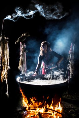 Güzel cadı demlemek bir iksir büyük kazan içinde. ? çok muskalardan enchantress ellerinde. Tencerede kaynayan iksiri. Kocakarı kurşun elleri