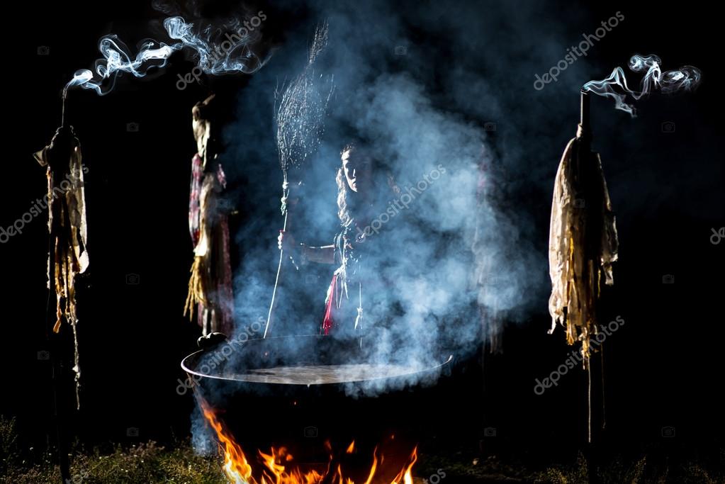 Beautiful witch brew a potion in the big cauldron. Boiling elixir in the pot. Enchantress is