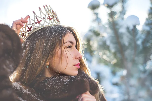 The Snow Queen . Young woman in crown in a snowy forest.