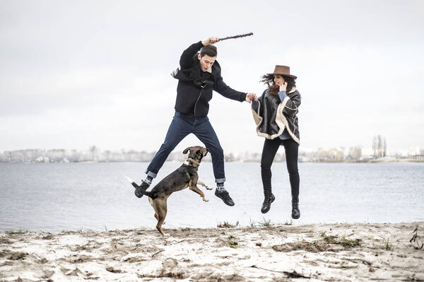 Мужчина и собака на пляже веселятся. Дог, играющий в высокие прыжки, все смеются
