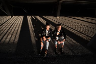 İki kız arkadaş oturur kaykay kentsel yaşam tarzı açık havada, Otopark.