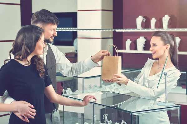 Vendedor dando bolsa de papel con compra para pareja . — Foto de Stock